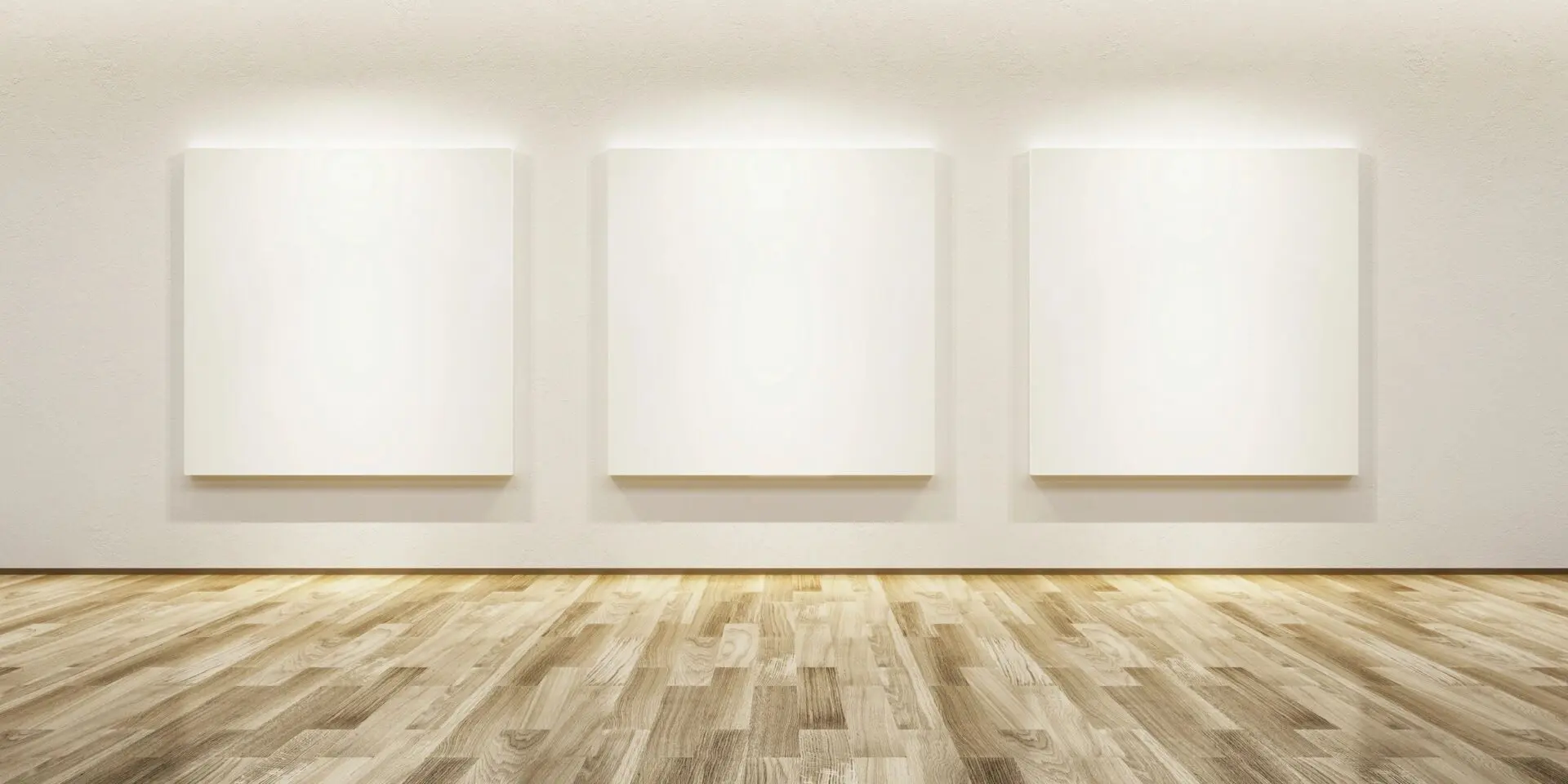 A room with three white canvases on the wall.
